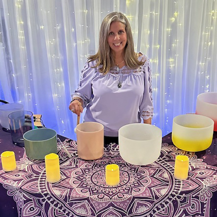 Lori at table with sound healing crystal singing bowls